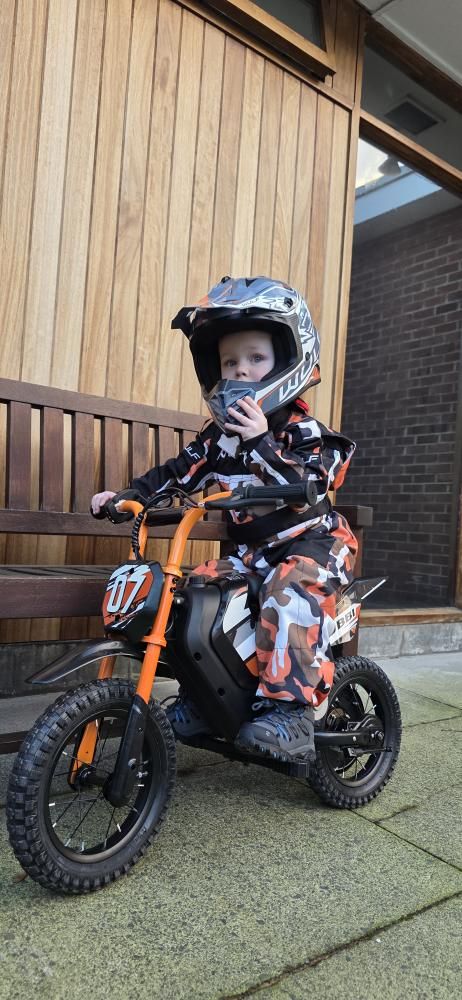 Kid riding a Kubbi electric dirt bike at speed off-road