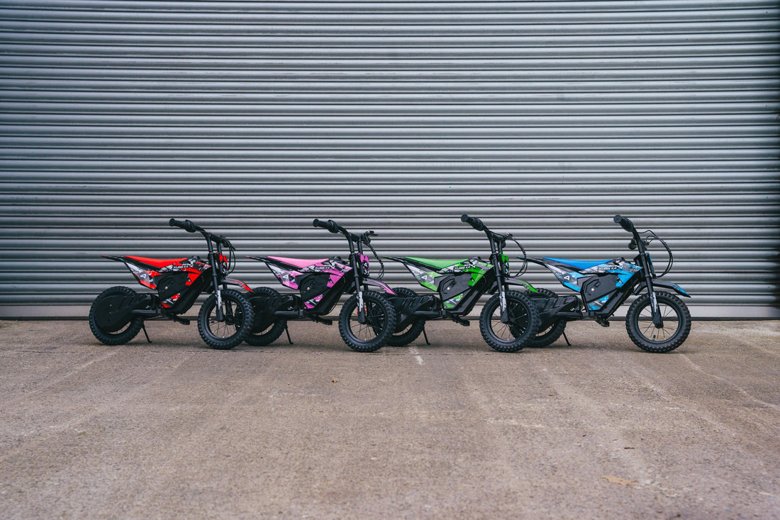 Five Kubbi electric dirt bikes lined up against a grey shutter