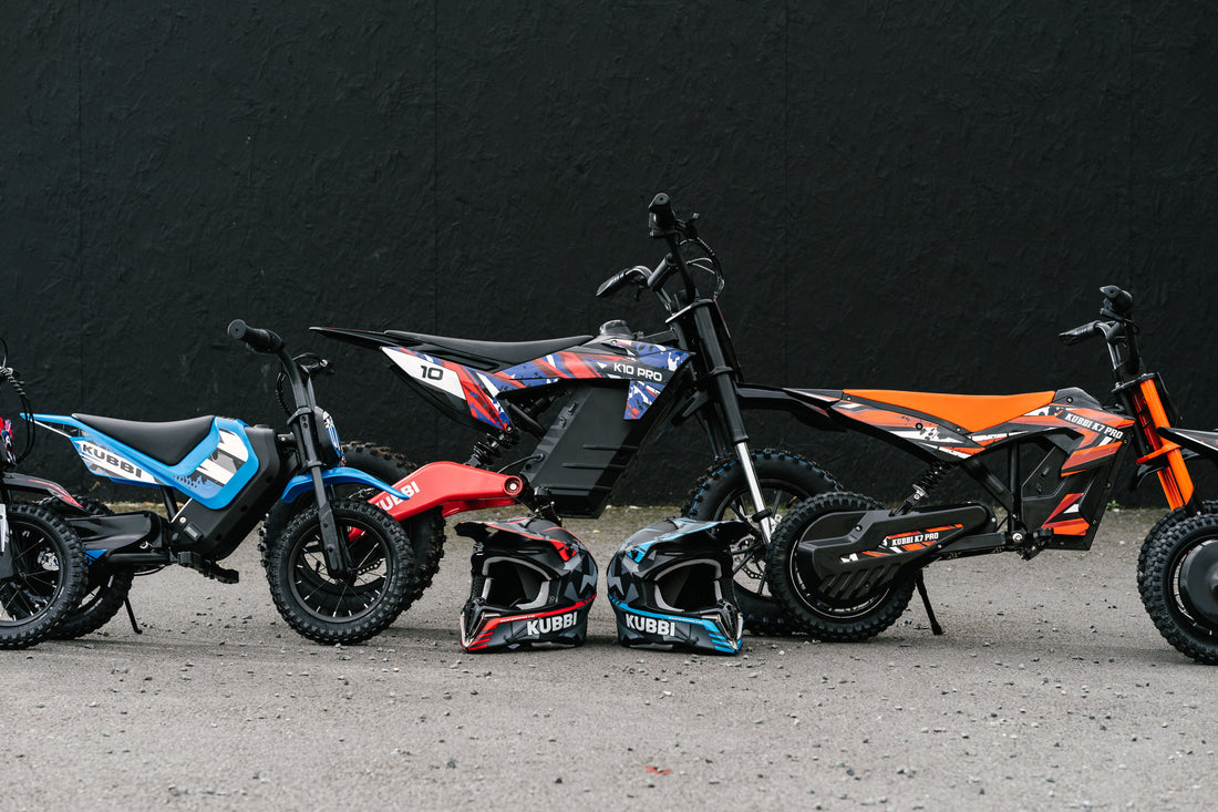 Four Kubbi electric dirt bikes lined up side-on in blue, pink, black and orange