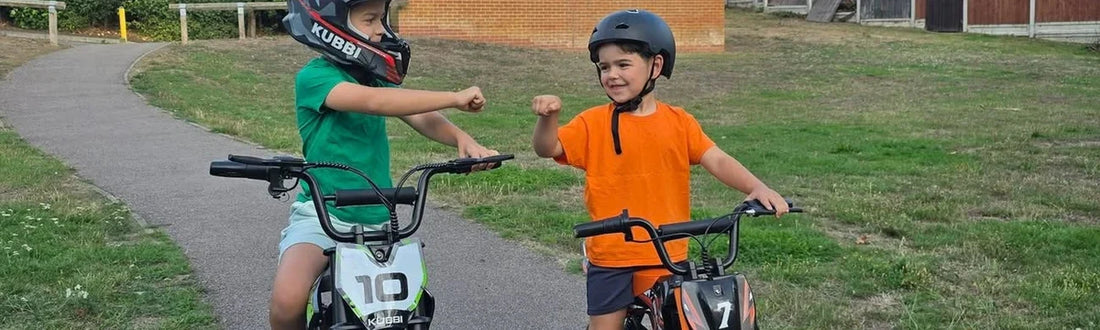 Two children in helmets outdoors on a grass path with their bikes