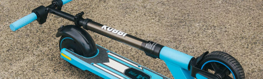 A folded Kubbi S4 Pro kids' electric scooter standing on tarmac