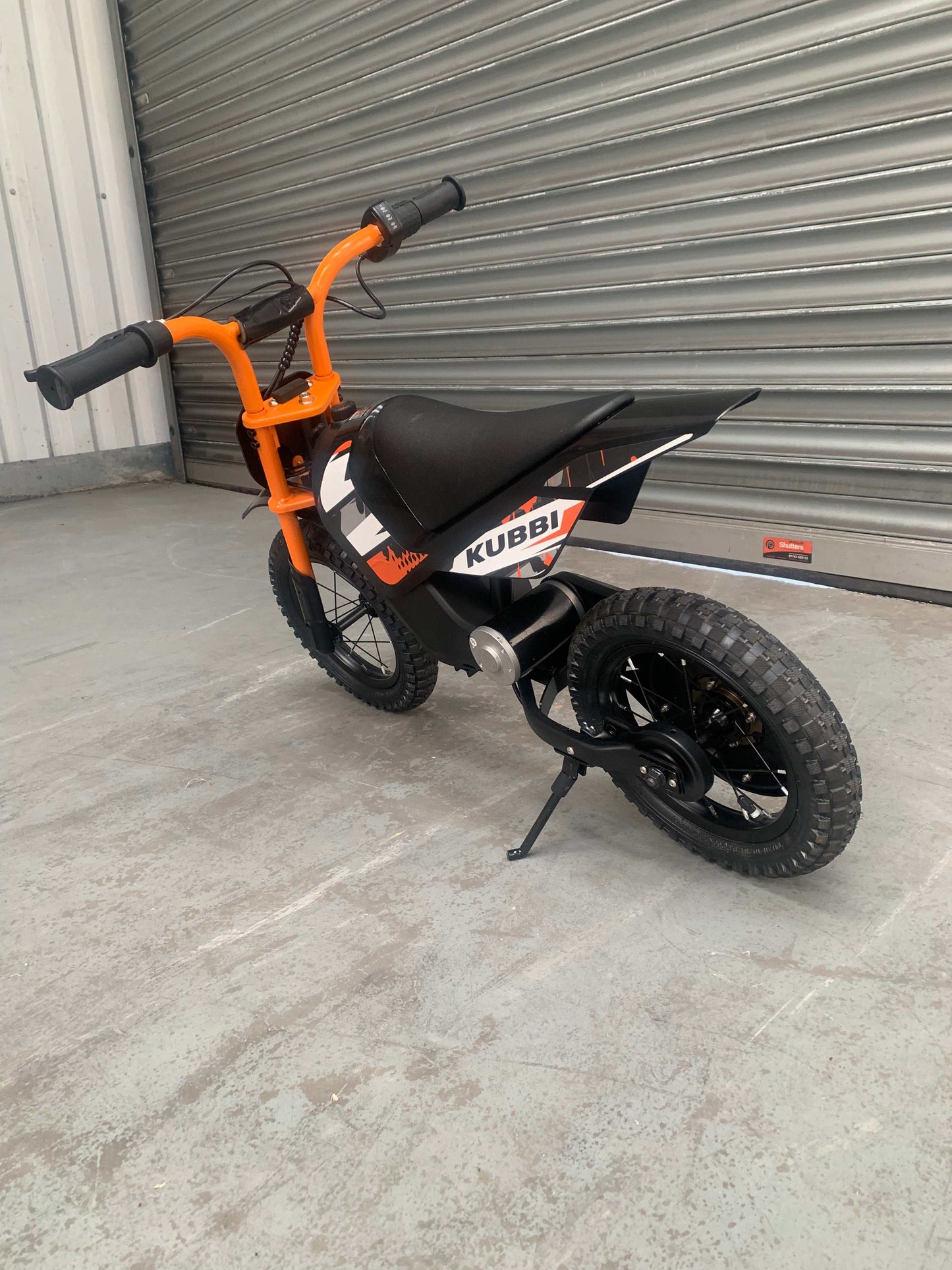 Kubbi Mini Electric Dirt Bike in orange, brand new and unused, warehouse deal display