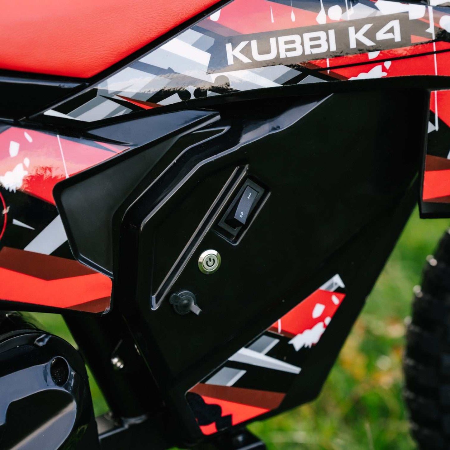 Close-up of Kubbi K4 Kids Electric Dirt Bike control panel with red and black design