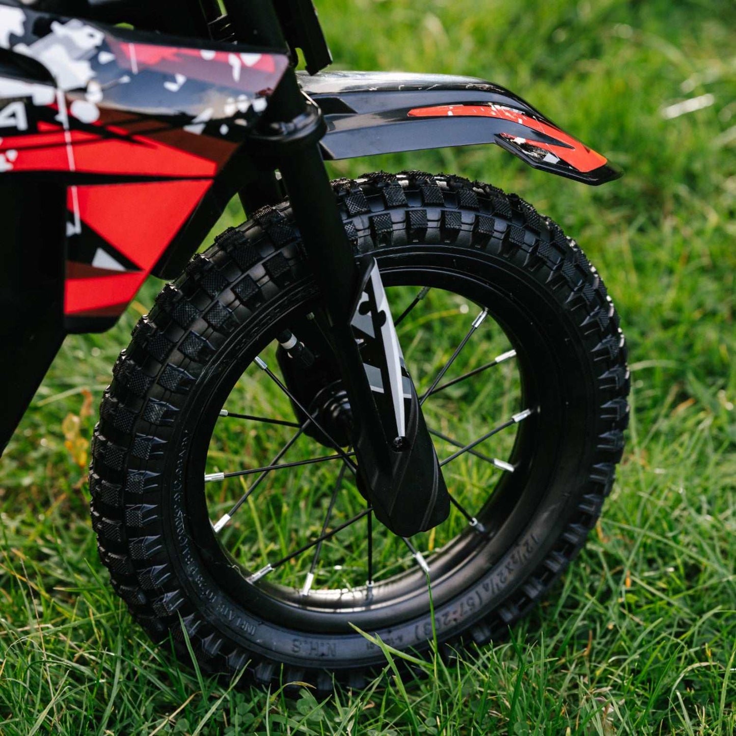 Close-up of Kubbi K4 Dirt Bike 12-inch knobby front tire on grass