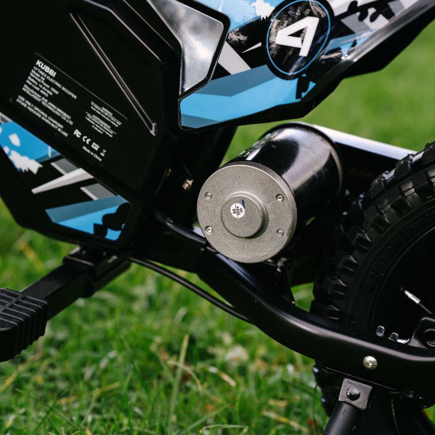Kubbi K4 Dirt Bike close-up of electric motor and black-blue frame on grass background